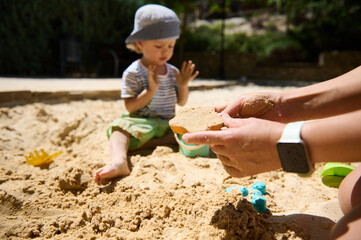 Child Playing in Sand with Parental Interaction on a Sunny Day