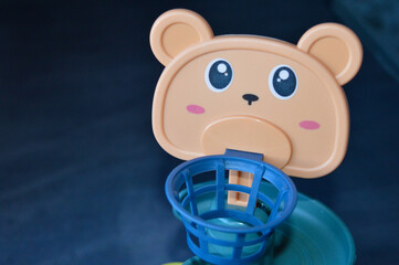 assembled colorful plastic ball ramp toy with bear face and spiral tracks. yellow balls rest on the...