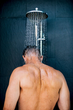 Man relaxing under a shower stream in modern bathroom