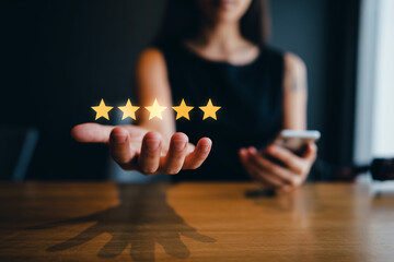 Customer feedback shown as five golden star rating on open hand with smartphone illustrating excellent service quality and business reputation