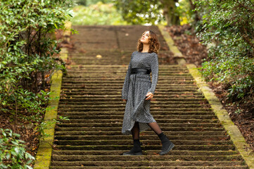 Fashionable Woman Walking on Mossy Stone Steps in Forest Setting