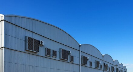 青空輝く工場群 力強く弧を描く屋根 静かに稼働する空調設備