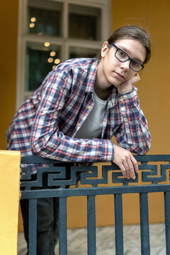 Teenage boy with long hair leaning on railing