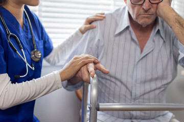 The doctor or Nurse wearing a white coat with a stethoscope is holding the hand of a patient in a...