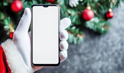 Santa holding smartphone with blank screen (mock up). Festive background.