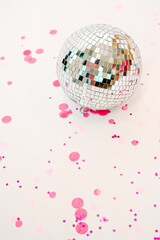 Colorful confetti surrounds a shining disco ball on a white background, capturing the spirit of celebration and fun at a party