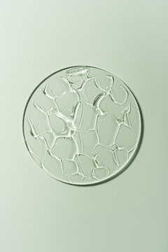 Transparent gel smear on glass against a green background