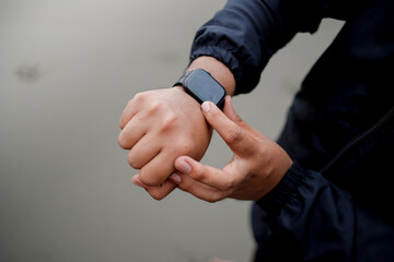 Obraz premium An athlete wears a smartwatch on his arm, is running and using an app. A male trainer in sportswear is on the beach.