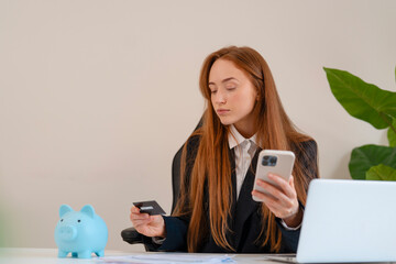 Young professional managing finances while using smartphone and credit card at modern office with a...