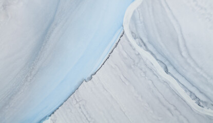 Unique patterns created with alcohol ink on a smooth surface showcasing blue and white hues