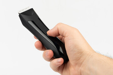 Hand holding sleek black hair clipper in neutral setting for grooming purposes