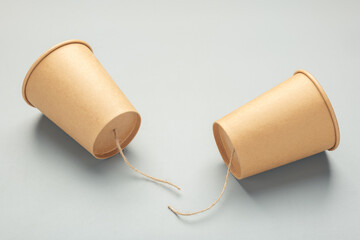 Two paper cups with a broken string between them, symbolizing failed communication,...