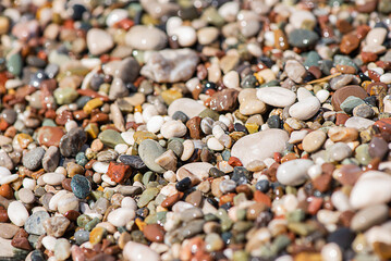 Sea colored pebbles on the beach, clear sea water
