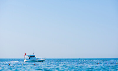 coastline with clear blue sea water and a small yacht in the background