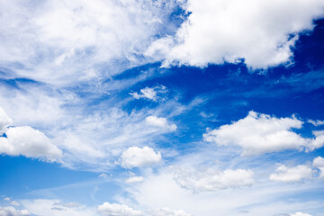 Bright blue sky filled with soft, white, and wispy clouds.