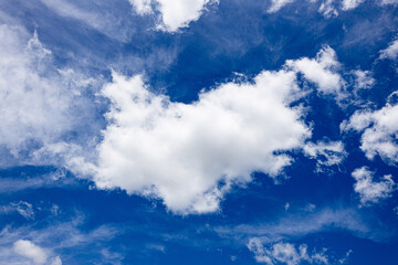 Bright blue sky filled with soft, white, and wispy clouds.