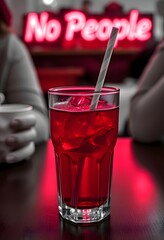 Red drink with ice and straw in glass cup on table with neon sign no people background