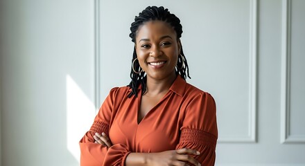 Portrait of smiling woman with braids and orange blouse arms crossed