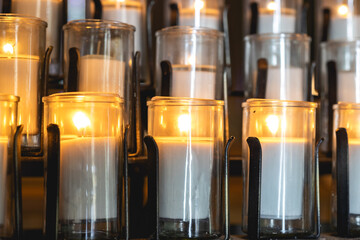 Lit candles inside a church with colorful stained glass windows.