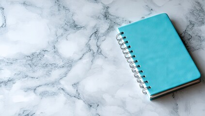 Light teal notebook on white marble surface