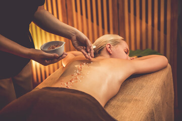 Woman customer having exfoliation treatment in luxury spa salon with warmth candle light ambient....