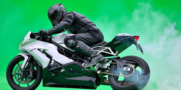 Motorcycle stunt with biker in black leather on sports bike making smoke and riding against chroma scale green screen