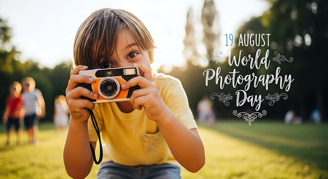 A young boy in a yellow shirt holds a vintage camera, aiming it towards the viewer in a sunny outdoor setting, with "World Photography Day" text overlay.