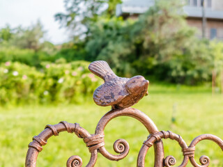 metal bird sculpture on the back of a bench. Bronze bird decor
