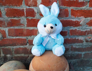 Blue Bunny Soft Toy Sitting Against Rustic Brick Wall