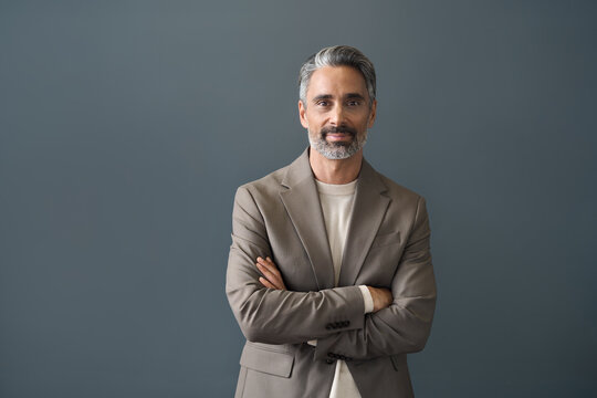 Happy middle aged business man CEO looking at camera. Smiling confident 50 years old mature professional businessman executive manager or entrepreneur standing at gray office wall background.