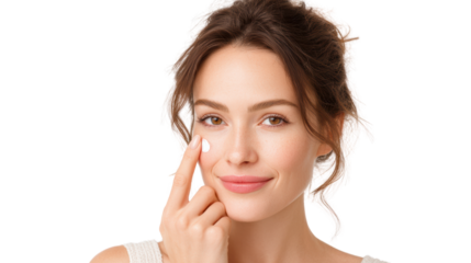 Young woman applying cream to her face, smiling happily, isolated on white background.