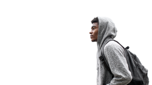Young man wearing hoodie and backpack, looking thoughtfully to the side against a white isolated background.