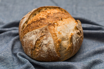 Fresh Loaf of Sourdough Bread on Blue cloth background straight out of the oven 