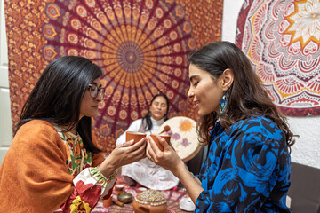 Women holding cups during organic cocoa ceremony for alternative medicine