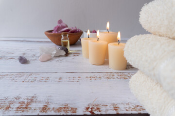 White painted spa table with towels, candles, oils, quartz, and flower petals