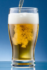 Beer pouring into glass on blue background