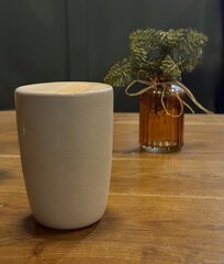 Cup of coffee with milk and honeycomb decoration on top, standing on a wooden table with small plant in a vase