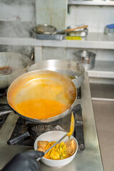Chef pouring fish sauce into bowl in restaurant kitchen