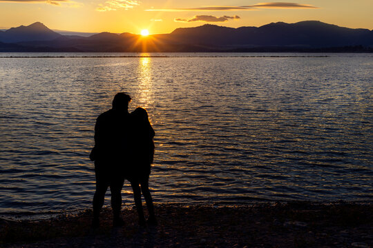 Young couple in love holding hands on a sandy beach near the sea at sunset spending romantic time on the weekend in summer. Sunrise by the sea bay