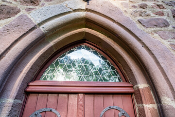 Heavy Gothic cathedral door with stone arch and stained glass