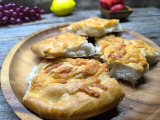 Golden bread with olive oil and small leaves. Focaccia bread on wooden plate.