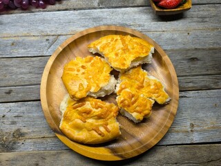 Golden bread with olive oil and small leaves. Focaccia bread on wooden plate.