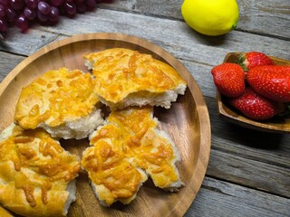 Golden bread with olive oil and small leaves. Focaccia bread on wooden plate.