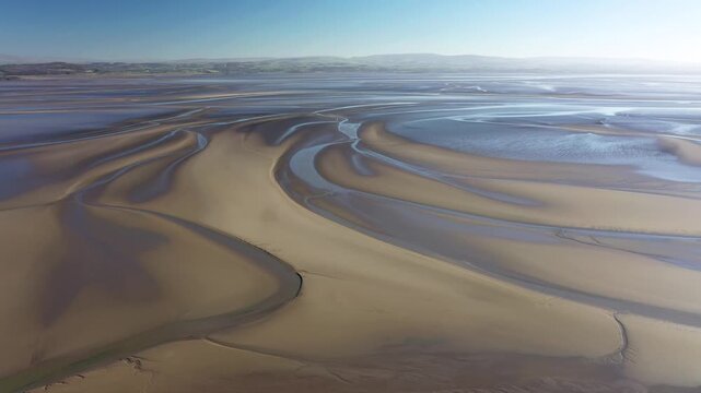 Looking east from Humphrey Head, Cumbria, England over extensive mudflats and tidal salt marsh where the River Kent estuary enters north end of Morecambe Bay. 4k video fly out back 