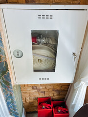 A vibrant red fire hose is carefully stored within a sleek white cabinet, which is a common and...