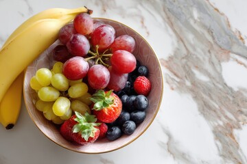 Obstschale mit frischen Beeren, Trauben und Bananen auf Marmoroberfläche