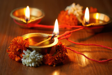 Diwali diya oil lamps with marigold flowers and red thread glowing warmly on a wooden surface