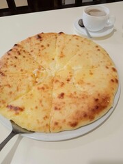 Traditional Ossetian cheese pie served in cozy Caucasian street cafe. Authentic national cuisine with golden crust and melted cheese filling