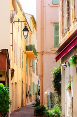 Street in Cannes with colorful houses and vintage street lamps under clear sky