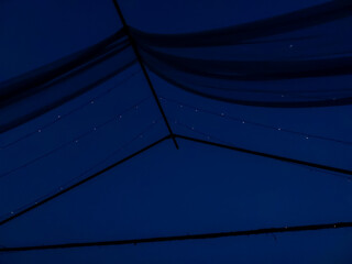 Night sky background with fairy lights sparkling in shack tent, nature photography